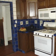 Before shot of kitchen with blue tiles. - cabinetry, countertop, floor, flooring, home, home appliance, kitchen, major appliance, room, brown