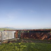 Exterior of house with rusted corten steel. Sustainable architecture, cloud, estate, grass, home, horizon, house, land lot, landscape, property, real estate, rural area, sky, sunlight, teal