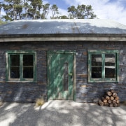 View of stone building with green windows and cottage, home, house, log cabin, property, real estate, roof, shack, shed, window, gray, black