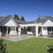 Exterior of house with white cladding, grey roof backyard, cottage, elevation, estate, facade, farmhouse, home, house, outdoor structure, property, real estate, residential area, roof, siding, villa, window, yard, blue