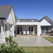 Exterior of house with white cladding, grey roof backyard, cottage, elevation, estate, facade, farmhouse, home, house, porch, property, real estate, residential area, roof, siding, villa, window, yard, gray, blue