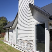 Exterior of house with white cladding and stone architecture, building, cottage, elevation, facade, home, house, real estate, residential area, siding, sky, window, white, blue