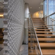 Wooden stairs with grey cutout feature wall. - architecture, baluster, building, daylighting, flooring, glass, handrail, interior design, lobby, stairs, structure, wall, gray