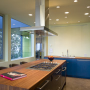 This kitchen features bright cabinetry and a wooden ceiling, countertop, daylighting, interior design, kitchen, real estate, room, window, brown