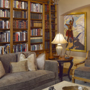 This home's interior was designed by Bruce Kading. bookcase, furniture, home, interior design, library, living room, room, shelving, wall, window, brown