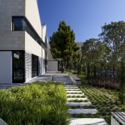 Exterior with landscaping and path. - Exterior with architecture, building, condominium, cottage, estate, facade, home, house, landscape, landscaping, property, real estate, residential area, sky, villa, walkway, blue