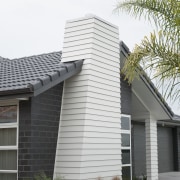 Exterior of single-storey house, dark stone cladding, and building, elevation, facade, home, house, property, real estate, residential area, roof, siding, window, white