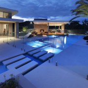 A large date palm balances the scale of architecture, condominium, estate, home, house, landscape lighting, leisure, lighting, property, real estate, resort, resort town, swimming pool, villa, blue