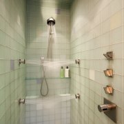 An array of water jets combine with the bathroom, ceiling, daylighting, floor, flooring, interior design, plumbing fixture, room, shower, sink, tile, wall, orange, brown