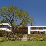 View of the entire home from the lawn. architecture, cottage, estate, facade, farmhouse, hacienda, home, house, landscape, mansion, plant, plantation, property, real estate, resort, sky, tree, villa, brown, blue