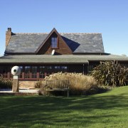 Exterior view with bush outside. - Exterior view cottage, estate, farmhouse, grass, home, house, landscape, outdoor structure, property, real estate, roof, sky, teal