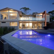 This home was designed and built by Graeme architecture, backyard, elevation, estate, facade, family car, home, house, landscape lighting, lighting, property, real estate, reflection, residential area, resort, swimming pool, villa, window, blue