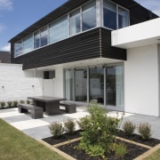 This 'Life at Home' home features paving from architecture, building, corporate headquarters, elevation, estate, facade, home, house, property, real estate, residential area, siding, window, gray