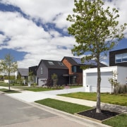 This street is part of a new initiative architecture, cottage, estate, facade, home, house, neighbourhood, property, real estate, residential area, sky, suburb, tree, white
