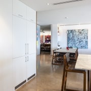 In this renovated home, the interior palette is ceiling, door, floor, flooring, interior design, room, table, wall, wood, gray, white