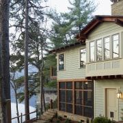 This lakefront house was remodeled to reference the building, cottage, facade, home, house, outdoor structure, property, real estate, siding, tree, window, white