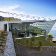 This glass-walled house, known as Jagged Edge, appears architecture, estate, house, property, real estate, sky, villa, water