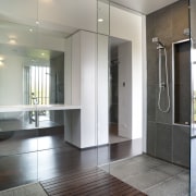 The full-height mirrored wall behind the vanity in door, floor, flooring, glass, interior design, lobby, property, real estate, gray