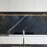 This classic kitchen by Robyn Labb offers modern countertop, floor, white, black