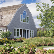 A porch and columns signal the formal entrance cottage, estate, farmhouse, garden, home, house, landscaping, plant, property, real estate, sky, yard, white