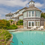 On this traditional Cape Cod house, a playful building, cottage, estate, facade, home, house, mansion, property, real estate, reflection, residential area, sky, villa, water, teal