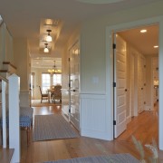 In this Cape Cod house, corridors lead off apartment, architecture, ceiling, daylighting, door, estate, floor, flooring, hardwood, home, house, interior design, laminate flooring, living room, lobby, real estate, room, wall, window, wood, wood flooring, gray, brown