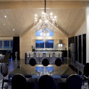 Dramatic black and white furnishings contrast the washed architecture, ceiling, chandelier, dining room, furniture, home, house, interior design, light fixture, lighting, lobby, room, table, black