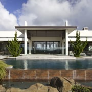 Rocks and grasses were planted around the lower architecture, elevation, estate, facade, home, house, official residence, property, real estate, residential area, swimming pool, villa, gray