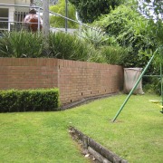 Because of its proximity to the interior living backyard, fence, garden, grass, grass family, landscape, landscaping, lawn, outdoor structure, plant, property, real estate, tree, walkway, wall, yard, green