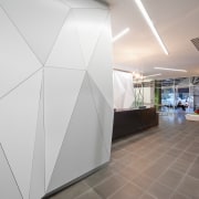 A multifaceted facade behind the reception desk of architecture, ceiling, daylighting, floor, interior design, product design, gray