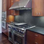 Crisp simplicity defines this contemporary kitchen in an cabinetry, countertop, cuisine classique, floor, flooring, hardwood, home appliance, interior design, kitchen, kitchen stove, room, under cabinet lighting, wood flooring, red