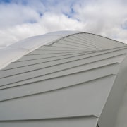 The roof was chosen in part for its angle, architecture, building, cloud, daylighting, daytime, line, roof, sky, gray