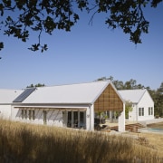 The gabled volumes in this country house reference barn, cottage, estate, farm, farmhouse, home, house, property, real estate, residential area, roof, rural area, sky, teal, brown