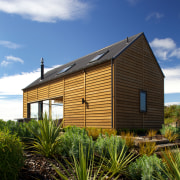 The cedar weatherboard exterior of this beach house architecture, cloud, cottage, facade, home, house, hut, plant, property, real estate, residential area, roof, shack, shed, siding, sky, tree