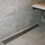 Luxe Linear Drain with a decorative steel grate. floor, flooring, plumbing fixture, tile, gray