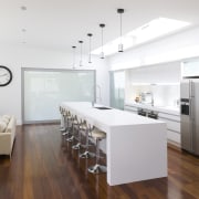 Contemporary white kitchen with large island. Internal sliding floor, flooring, interior design, interior designer, kitchen, living room, real estate, wood flooring, white