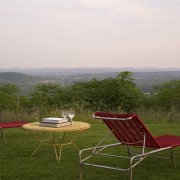 Sitting high on a natural plateau, this house chair, field, furniture, grass, grassland, house, landscape, leisure, meadow, outdoor furniture, plain, plant, rural area, sky, sunlounger, table, tree, brown, white