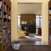 With bookshelves lining both sides, the entry to bookcase, bookselling, furniture, institution, interior design, library, library science, living room, public library, shelf, shelving, orange