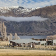 This large contemporary courtyard house nestles into the alps, cloud, elevation, fell, highland, hill, landscape, mountain, mountain range, mountainous landforms, national park, ranch, rural area, sky, snow, tree, wilderness, winter, gray