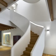 A dramatic sculptural staircase winds up all three architecture, ceiling, daylighting, floor, handrail, hardwood, home, house, interior design, product design, stairs, wood, gray