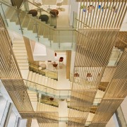 The staircase running through the atrium of this architecture, ceiling, daylighting, home, interior design, stairs, wood, orange, brown