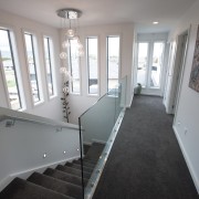 A double-height atrium brings light into the stairwell architecture, ceiling, daylighting, estate, floor, flooring, handrail, home, house, interior design, property, real estate, room, stairs, wall, window, wood, gray