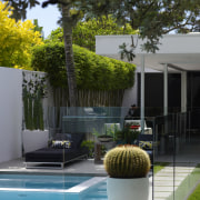 Sun lounges create a relaxing patio area within architecture, arecales, backyard, courtyard, home, house, landscaping, outdoor structure, palm tree, plant, property, real estate, residential area, swimming pool, tree, brown