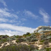 While the oceanside site provides a great outlook, cloud, coast, hill, house, mountain, plant community, real estate, shrubland, sky, terrain, blue