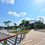 Public amenities at the Singapore Sports Hub include area, boardwalk, cloud, estate, leisure, real estate, recreation, residential area, sky, tree, walkway, teal