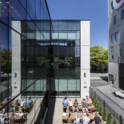 This side courtyard extends the staff cafeteria at apartment, architecture, building, condominium, corporate headquarters, daytime, facade, headquarters, house, mixed use, real estate, window, blue, black