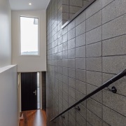 A welcoming double-height entrance with a honed, stacked architecture, bathroom, daylighting, floor, flooring, glass, handrail, home, house, interior design, room, tile, wall, gray