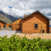 This new home is visually enticing in its cottage, elevation, facade, farmhouse, home, house, hut, land lot, landscape, log cabin, mountain, property, real estate, roof, rural area, sky, gray, brown