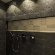 The custom Italian porcelain tile inset in this architecture, bathroom, darkness, floor, flooring, interior design, light, public toilet, reflection, room, texture, tile, wall, black