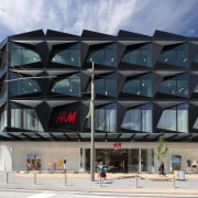 High-profile brand H&amp;M literally has a high-profile facade architecture, building, commercial building, mixed use, structure, gray, black